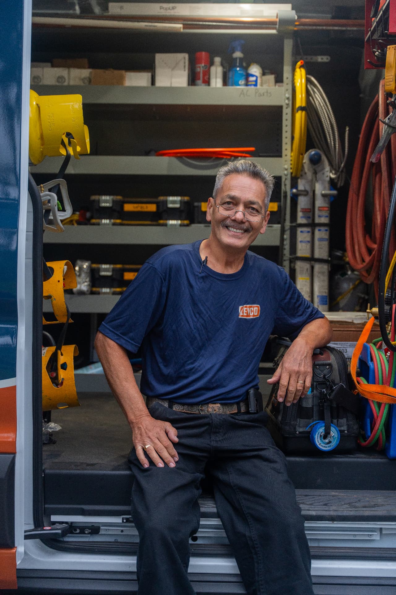 Levco technician sitting in the doorway of a fully stocked service van