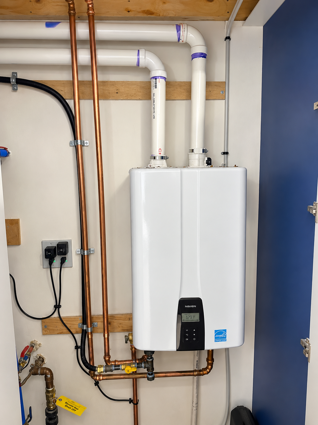 Completed wall-mounted Navien tankless water heater installation with copper piping