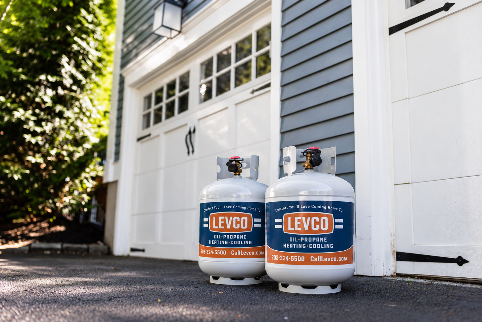 Two white Levco propane grill tanks parked in the driveway of a Connecticut home