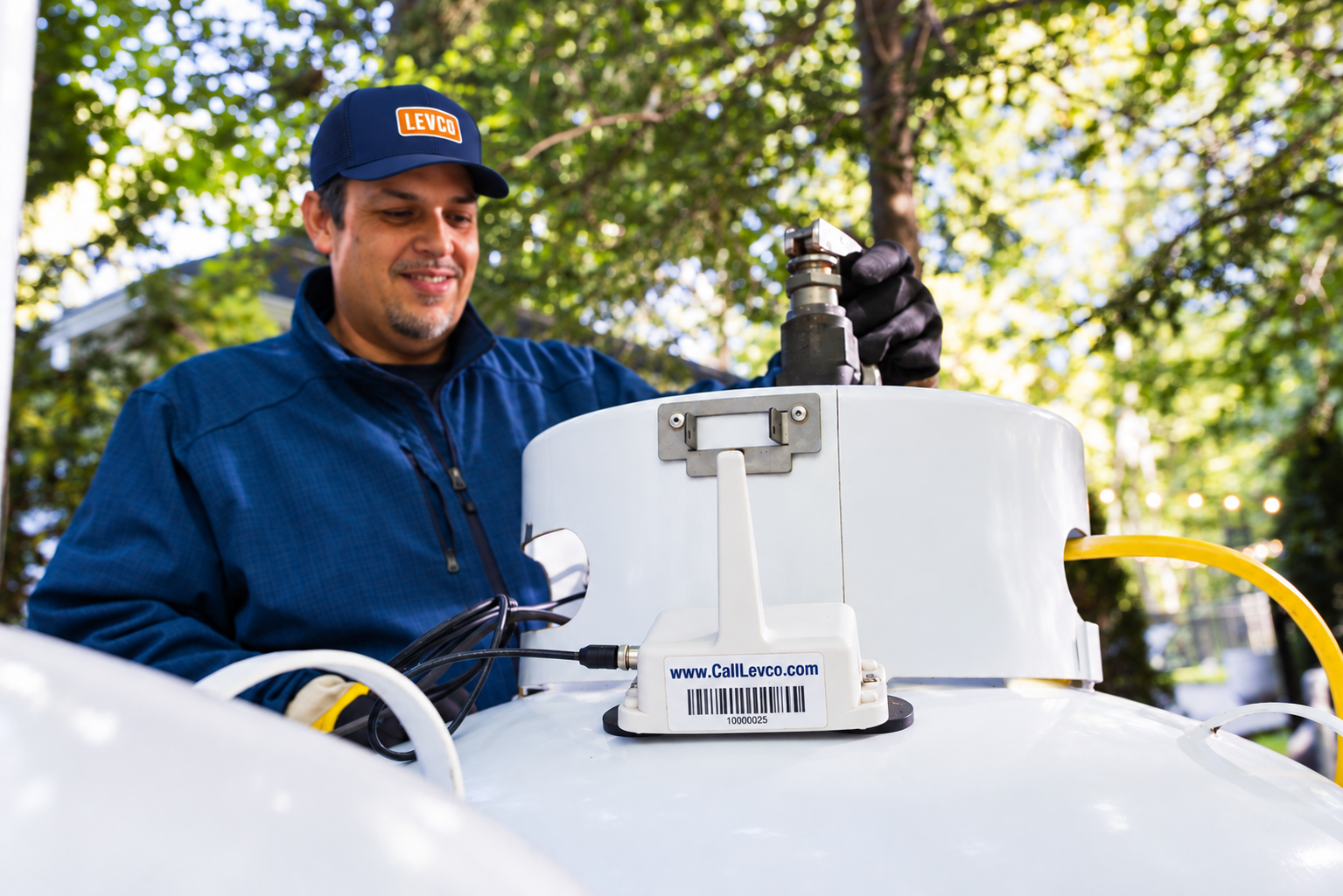 Levco technician beside a residential propane tank with wireless monitoring