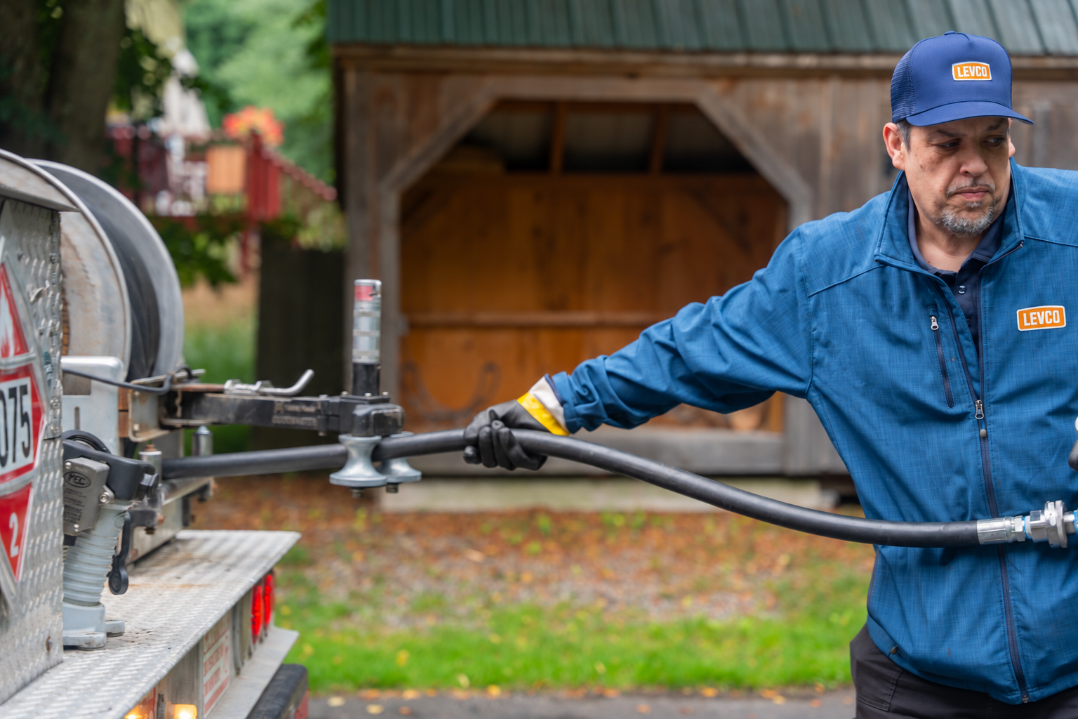 Levco propane driver connecting a delivery hose from the truck beside a Connecticut home