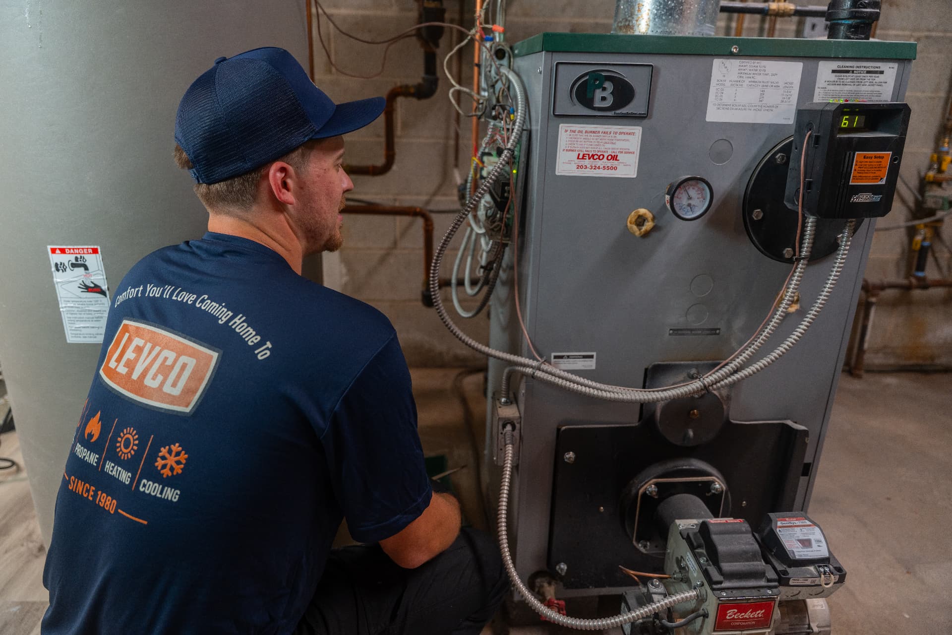 Levco technician assessing an older oil-fired heating system for repair or replacement