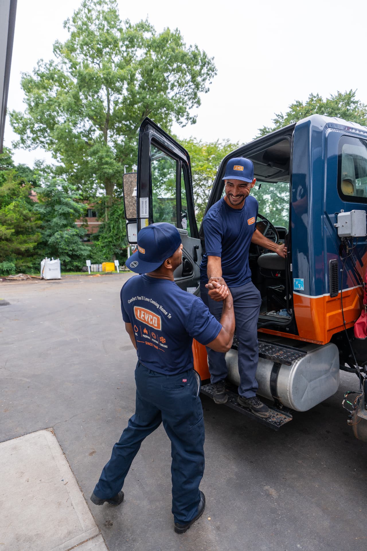 Two Levco team members greeting each other beside a Levco service truck