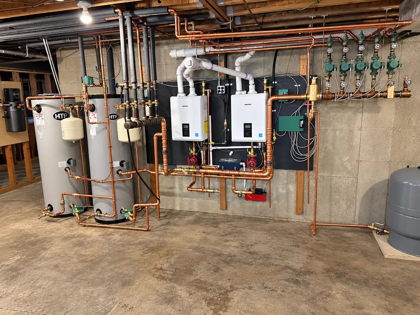 Completed Levco installation with two wall-mounted heating units, two storage tanks, and finished copper piping